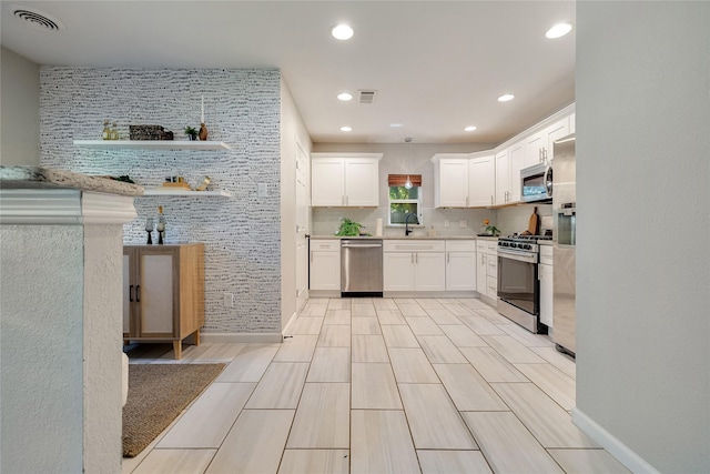 kitchen featuring tasteful backsplash, appliances with stainless steel finishes, white cabinetry, and pendant lighting