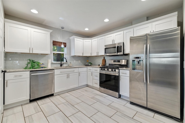 kitchen with white cabinetry, stainless steel appliances, backsplash, decorative light fixtures, and sink