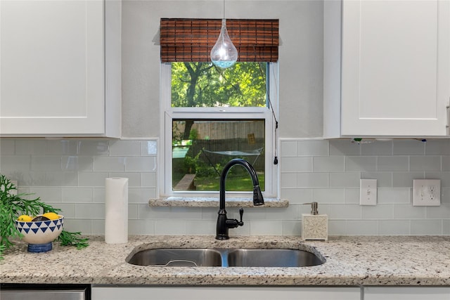 room details with decorative light fixtures, sink, white cabinetry, and light stone countertops