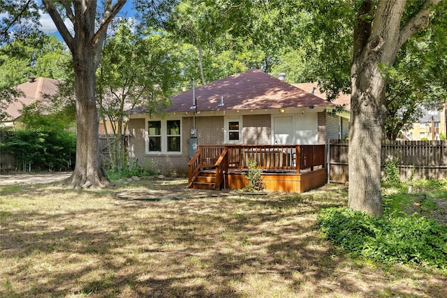 rear view of property with a wooden deck and a lawn