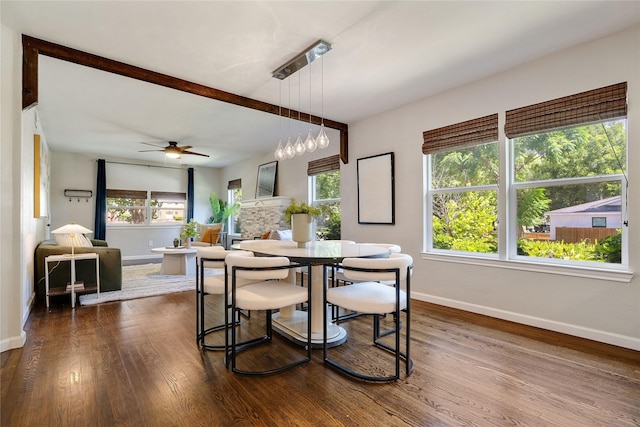 dining room with ceiling fan, dark wood-type flooring, and a fireplace