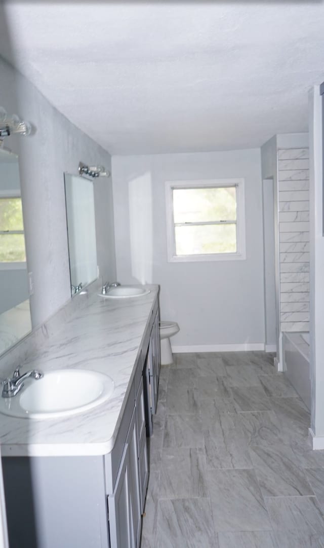 full bathroom with a wealth of natural light, vanity, toilet, and tile patterned flooring