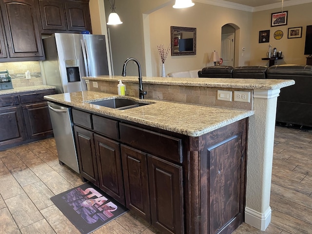 kitchen with a kitchen island with sink, sink, stainless steel appliances, and ornamental molding