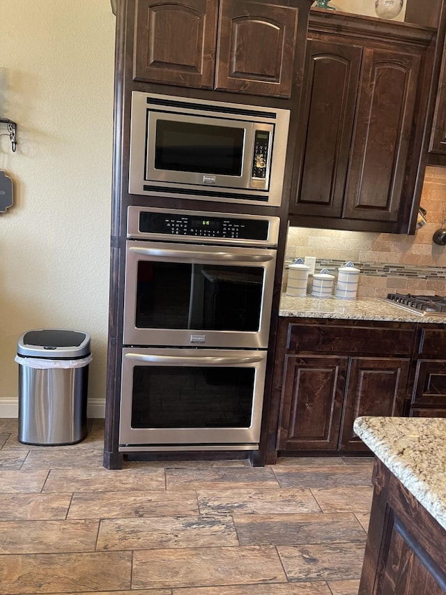 kitchen featuring light stone countertops, appliances with stainless steel finishes, and dark brown cabinets