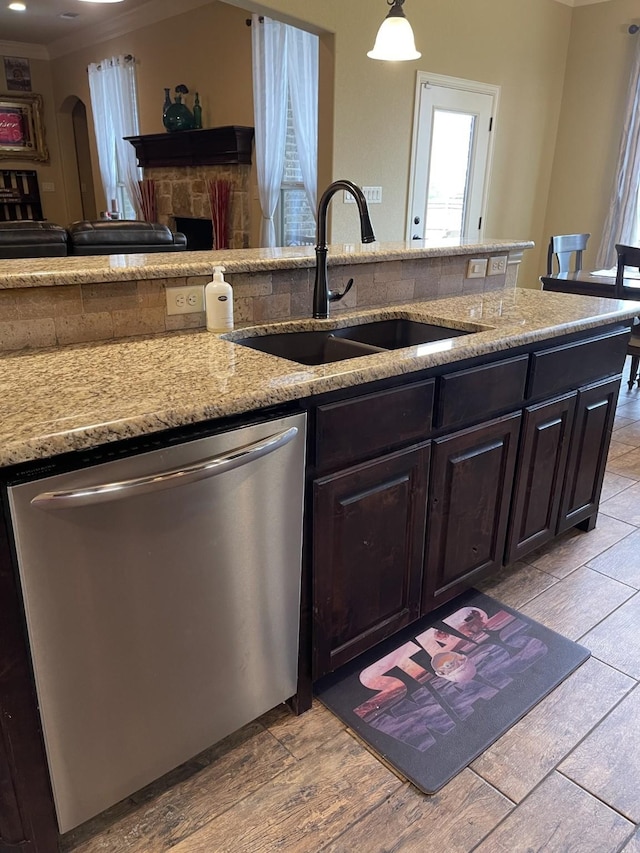 kitchen featuring decorative light fixtures, light hardwood / wood-style floors, sink, light stone counters, and stainless steel dishwasher