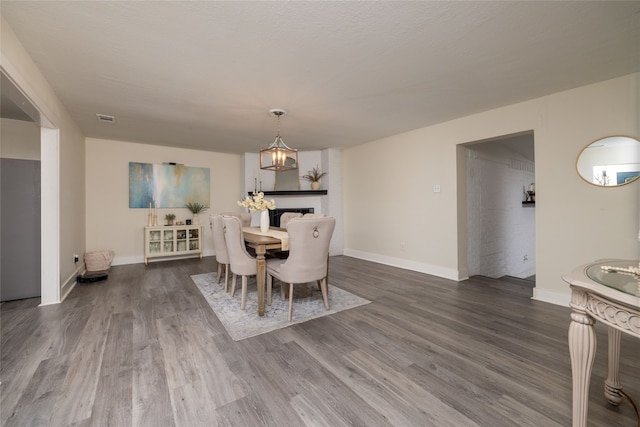 dining area with a chandelier, wood-type flooring, and a fireplace