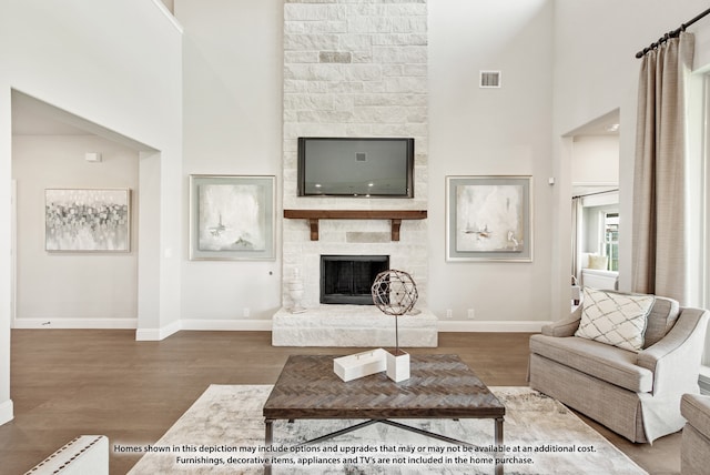 living room featuring a towering ceiling, wood-type flooring, and a fireplace