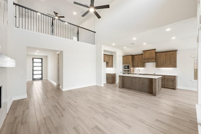 kitchen featuring sink, light wood-type flooring, appliances with stainless steel finishes, ceiling fan, and a kitchen island with sink