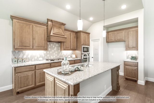 kitchen featuring appliances with stainless steel finishes, light stone counters, an island with sink, lofted ceiling, and dark wood-type flooring