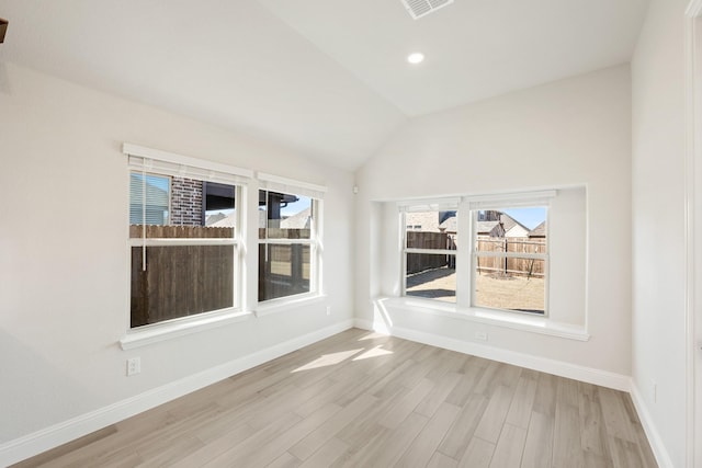 spare room featuring lofted ceiling and light hardwood / wood-style floors