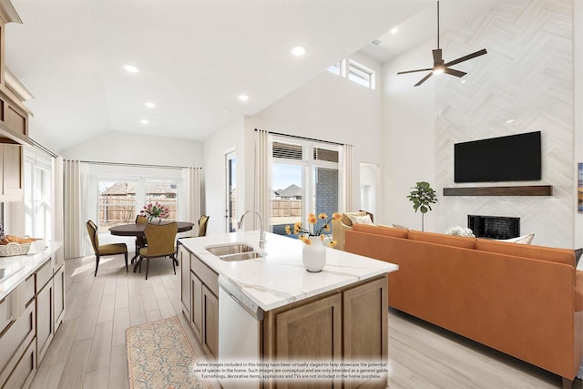 kitchen with a healthy amount of sunlight, a premium fireplace, a kitchen island with sink, and sink