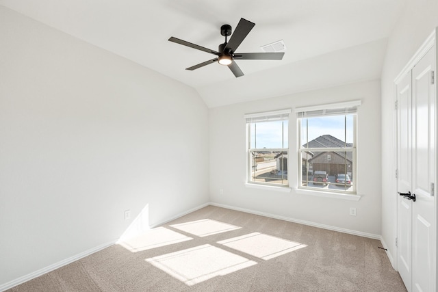 spare room featuring vaulted ceiling, light carpet, and ceiling fan