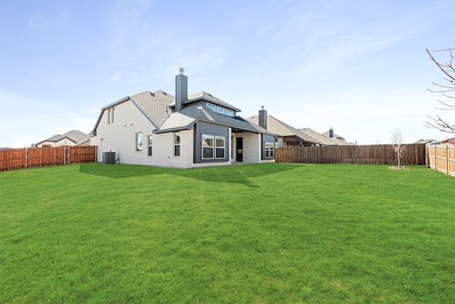 rear view of property with central AC unit and a lawn