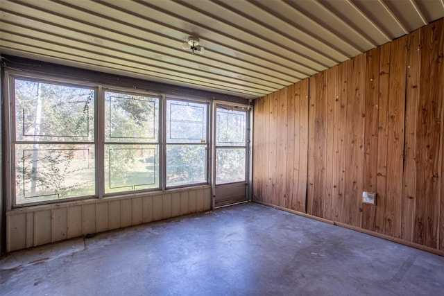 spare room featuring concrete flooring and wood walls