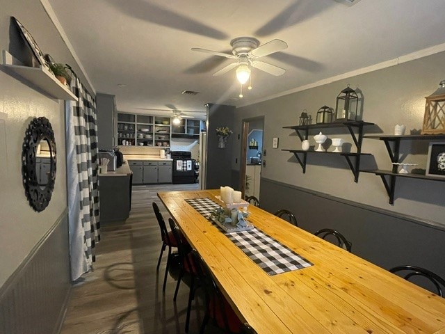 dining area with ceiling fan, crown molding, and dark wood-type flooring