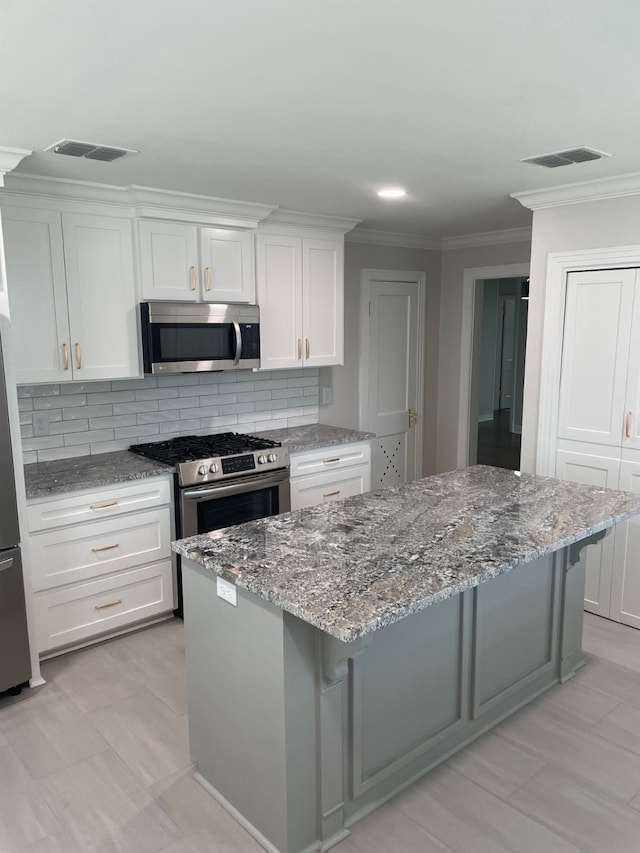 kitchen with a kitchen island, a breakfast bar, white cabinetry, backsplash, and stainless steel appliances