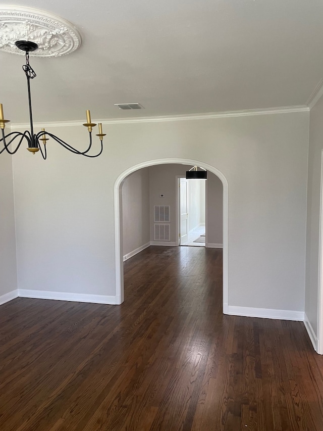 empty room featuring ornamental molding, dark hardwood / wood-style floors, and a chandelier