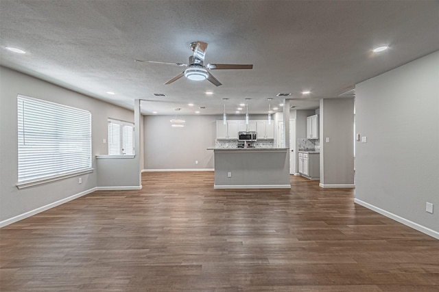 unfurnished living room featuring a textured ceiling, dark wood-type flooring, and ceiling fan