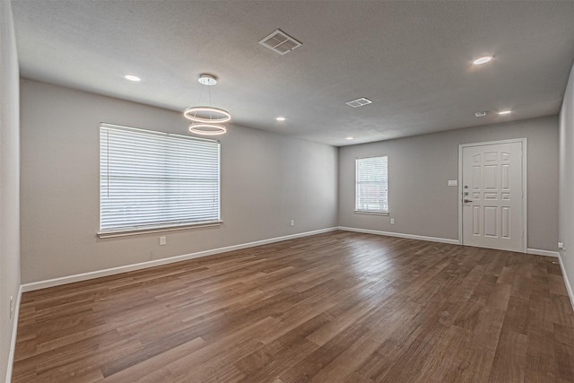 empty room featuring a textured ceiling and dark hardwood / wood-style floors