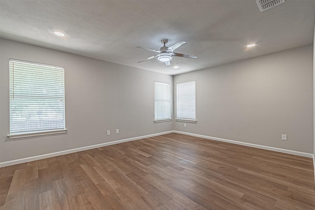 unfurnished room featuring ceiling fan, wood-type flooring, and a healthy amount of sunlight