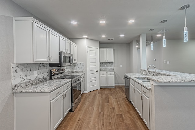 kitchen with sink, light hardwood / wood-style floors, stainless steel appliances, white cabinets, and decorative backsplash