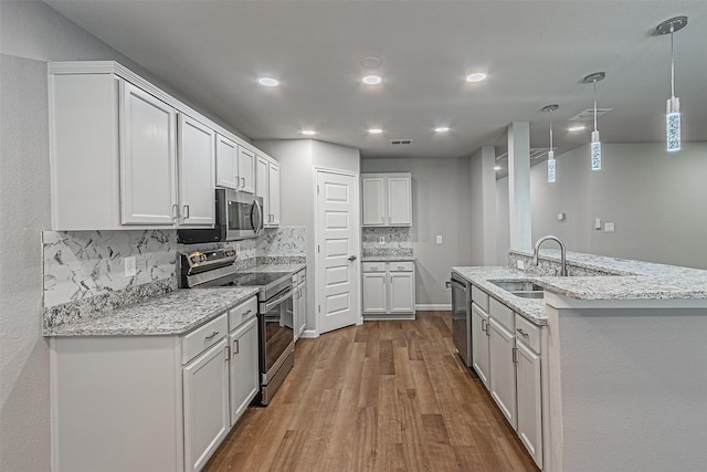 kitchen with backsplash, sink, white cabinetry, light wood-type flooring, and stainless steel appliances