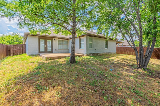 back of house featuring a lawn, french doors, and a patio