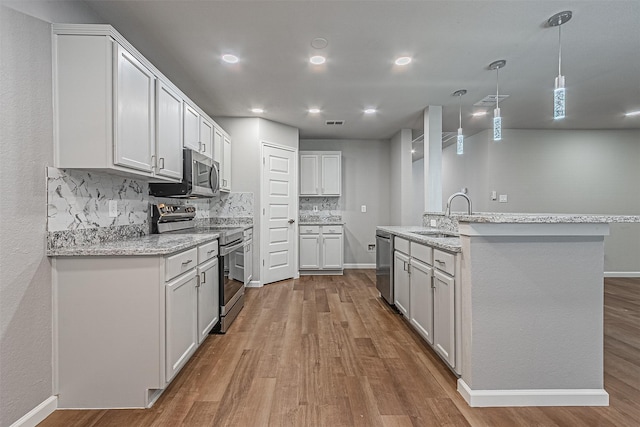 kitchen featuring light hardwood / wood-style floors, sink, white cabinetry, light stone countertops, and stainless steel appliances