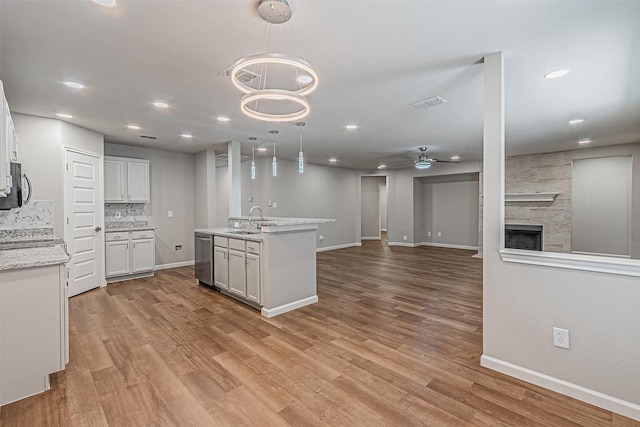 kitchen featuring ceiling fan, a fireplace, pendant lighting, sink, and white cabinetry