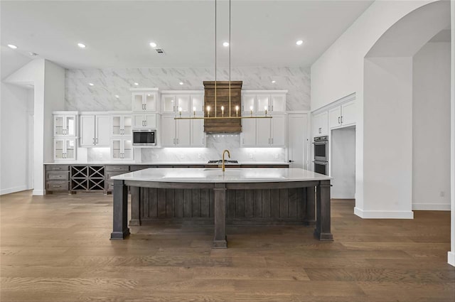 kitchen featuring a kitchen island with sink, dark hardwood / wood-style flooring, pendant lighting, and stainless steel appliances