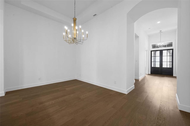 spare room with french doors, a chandelier, and dark hardwood / wood-style flooring