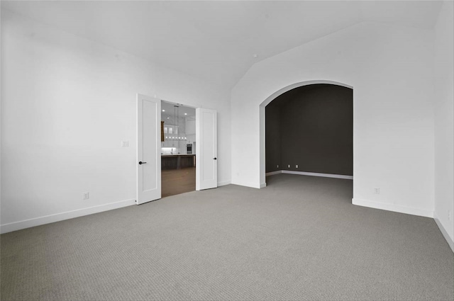 carpeted spare room with lofted ceiling