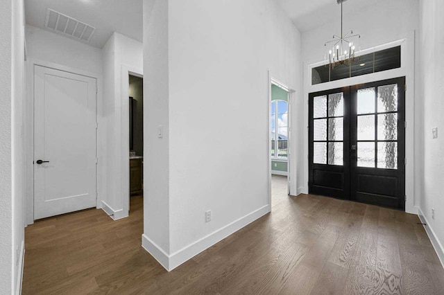 entryway featuring french doors, a chandelier, and dark wood-type flooring