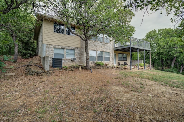 back of property featuring a carport, brick siding, and a wooden deck