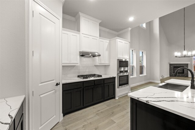 kitchen featuring light stone countertops, stainless steel appliances, sink, white cabinetry, and hanging light fixtures