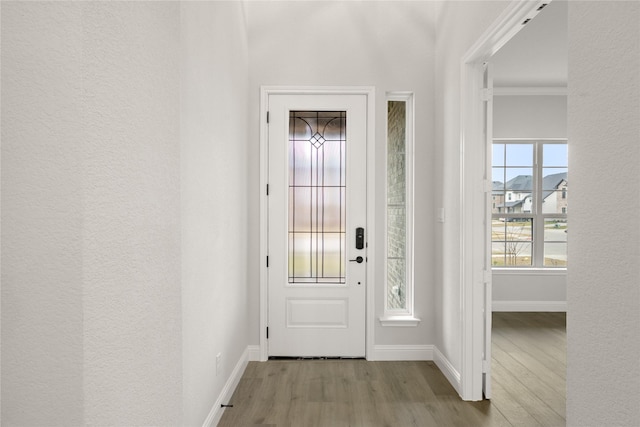 doorway to outside with light hardwood / wood-style floors and ornamental molding