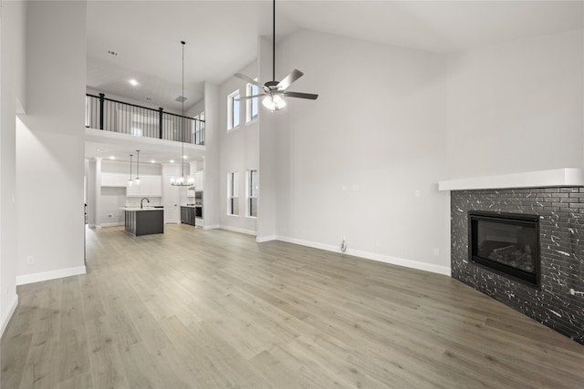 unfurnished living room featuring hardwood / wood-style flooring, ceiling fan, a towering ceiling, and sink