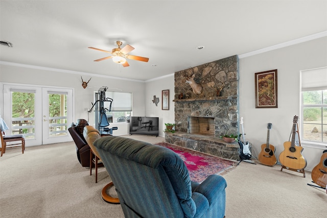 carpeted living room featuring a stone fireplace, crown molding, ceiling fan, and a healthy amount of sunlight