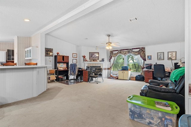 carpeted living room with a textured ceiling, a tile fireplace, and ceiling fan