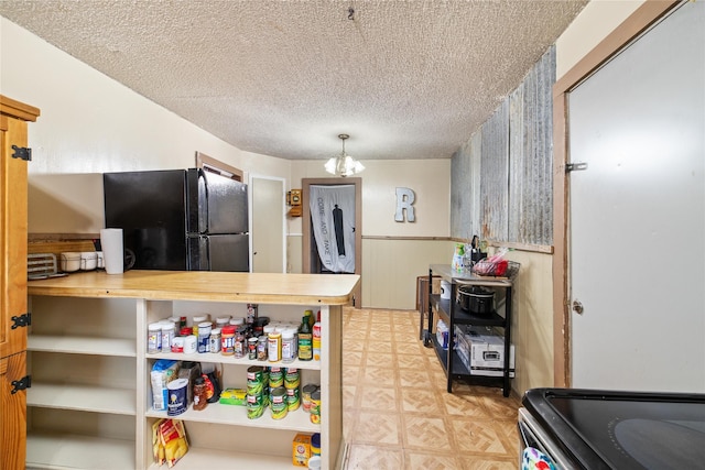 kitchen featuring a textured ceiling, a notable chandelier, freestanding refrigerator, light floors, and decorative light fixtures