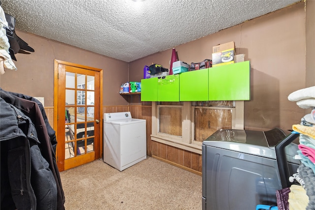 laundry room featuring light colored carpet, washer and dryer, and a textured ceiling