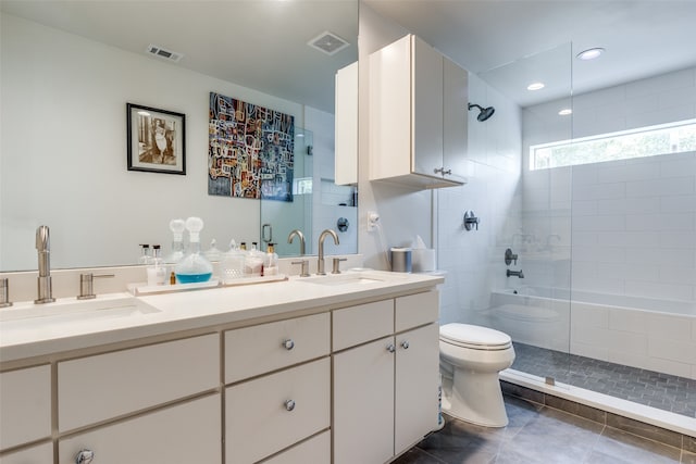 bathroom featuring vanity, tile patterned flooring, toilet, and tiled shower