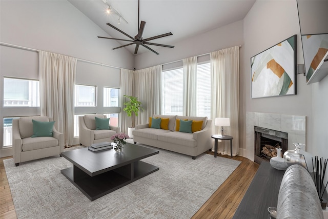 living area with high vaulted ceiling, track lighting, wood finished floors, a fireplace, and ceiling fan