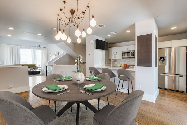 dining area featuring ceiling fan with notable chandelier and light hardwood / wood-style flooring