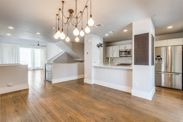 kitchen featuring white cabinets, decorative backsplash, appliances with stainless steel finishes, and light hardwood / wood-style floors