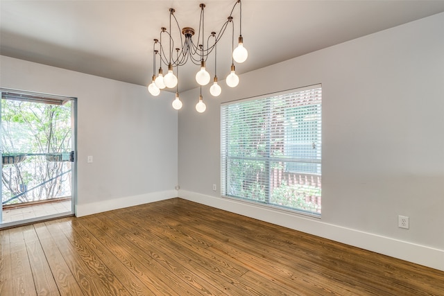 unfurnished room featuring an inviting chandelier and hardwood / wood-style floors