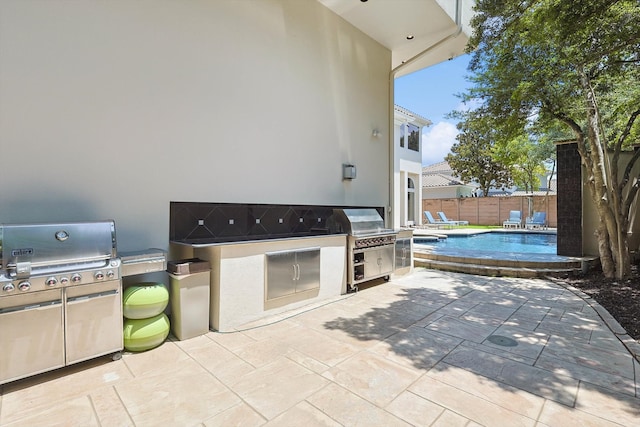 view of patio featuring area for grilling, a fenced in pool, and an outdoor kitchen