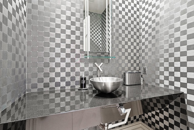 bathroom featuring decorative backsplash, sink, and tile walls