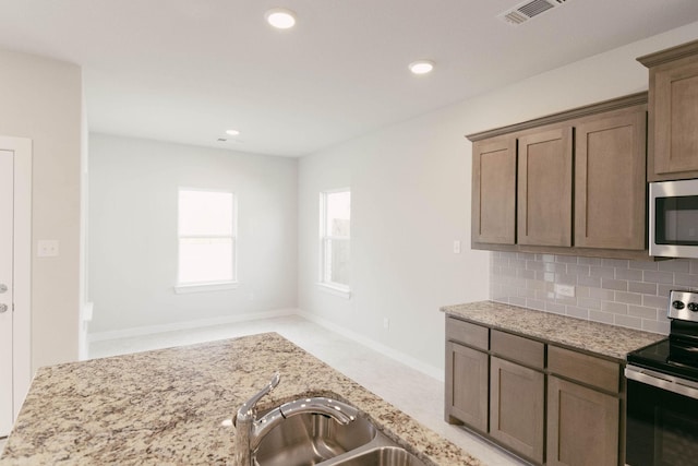 kitchen featuring appliances with stainless steel finishes, light stone countertops, and tasteful backsplash