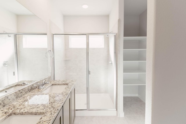 bathroom with a shower with door, tile patterned floors, and vanity